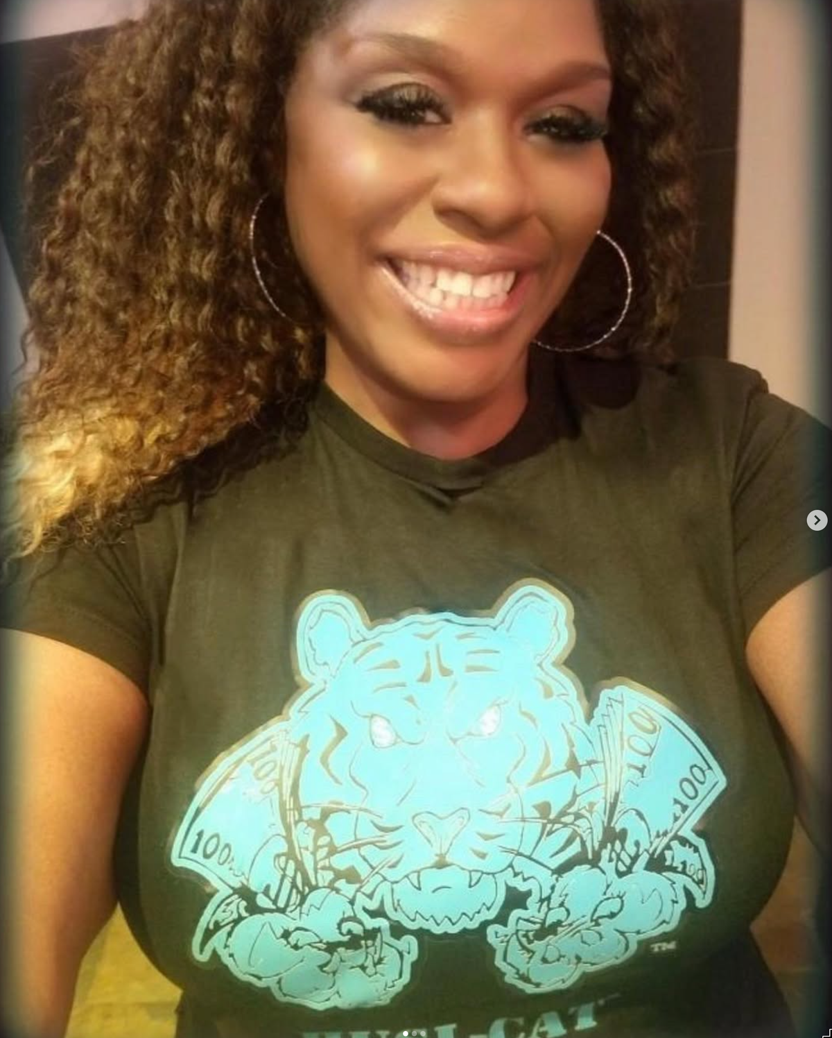 Smiling woman wearing a black HUSL-CAT T-shirt with a tiger graphic