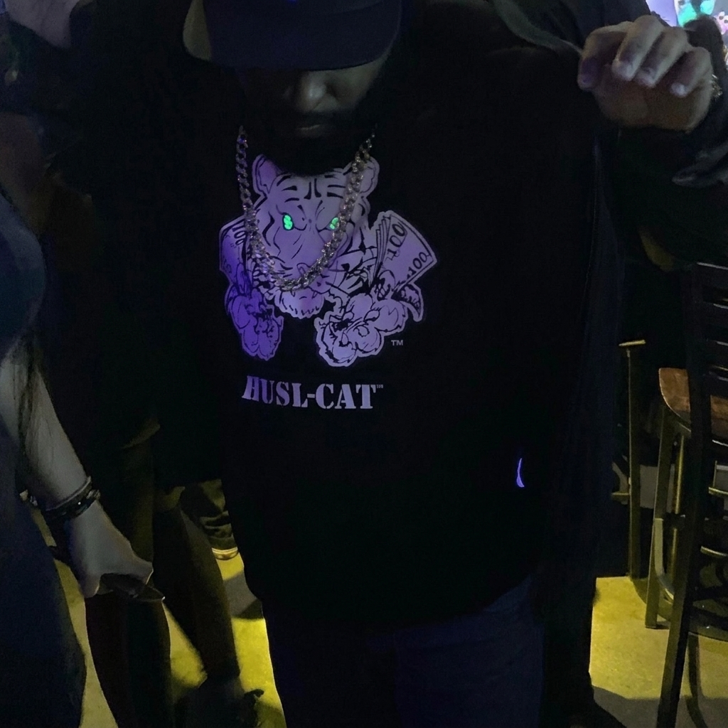 Man wearing a black HUSL-CAT T-shirt with a purple tiger graphic